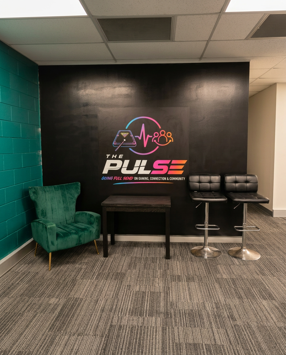 The Pulse lounge corner with the mural logo on a black feature wall, a green armchair, table and bar stools