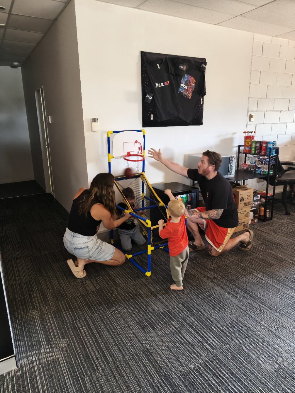 A family playing the mini basketball arcade game at Open Day