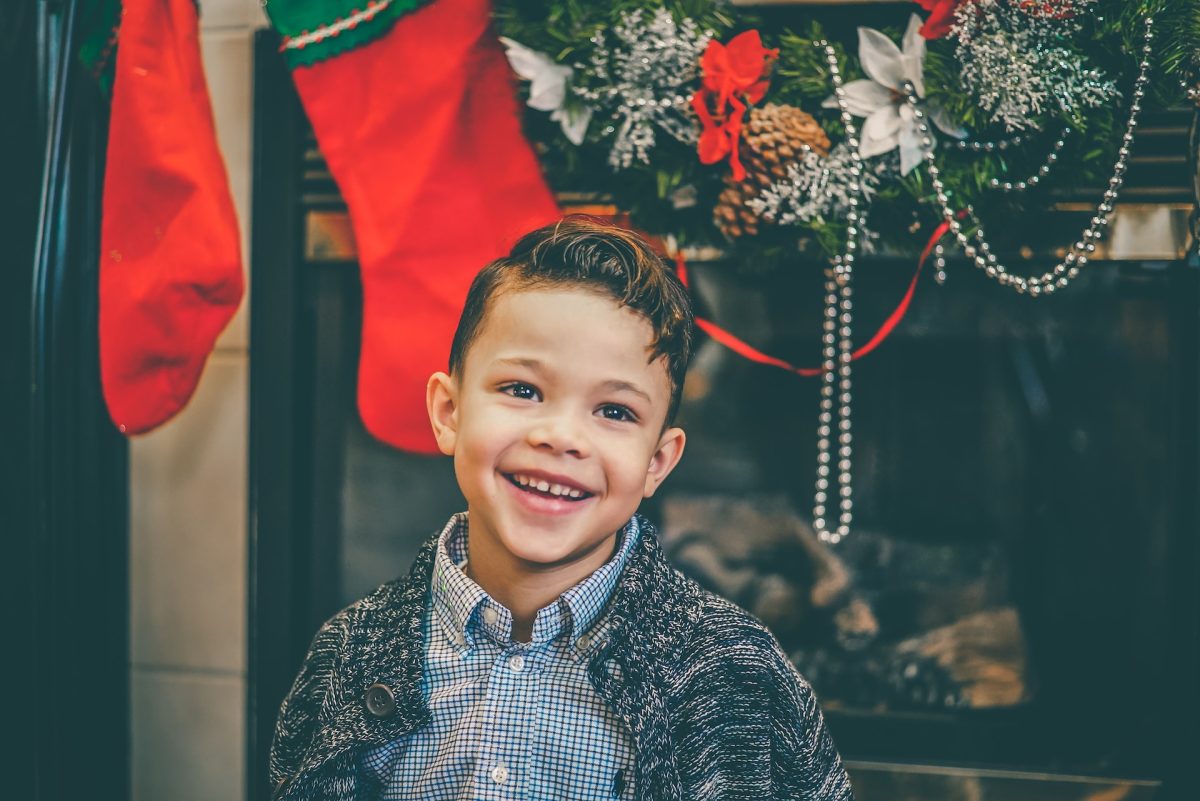 Child smiling with Christmas stocking in background in defiance of disability.